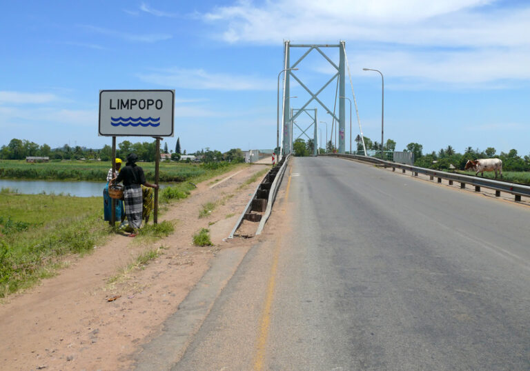 Limpopo, Mozambique - December 11, 2008: Two unknown women stand near a street sign. The bridge and the road bridge over the river Limpopo.